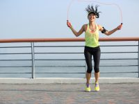young fitness woman jumping rope at  seaside